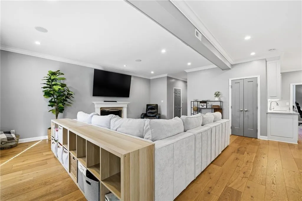 Living area with light wood finished floors, ornamental molding, recessed lighting, and a fireplace