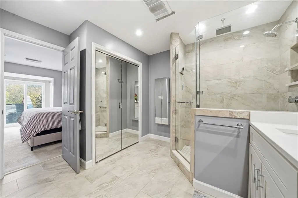 Ensuite bathroom featuring a marble finish shower, vanity, and light marble finish floors
