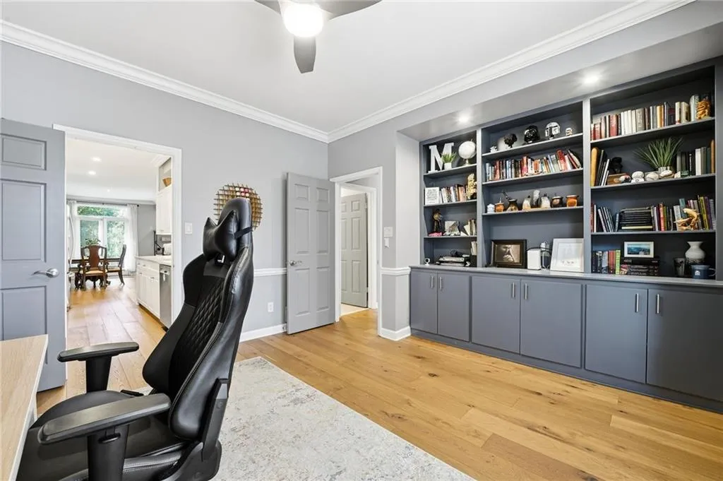Office area featuring light wood-type flooring, ornamental molding, a ceiling fan, and built in features