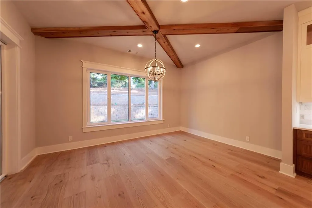 Unfurnished dining area with coffered ceiling, a chandelier, beam ceiling, and light hardwood / wood-style flooring