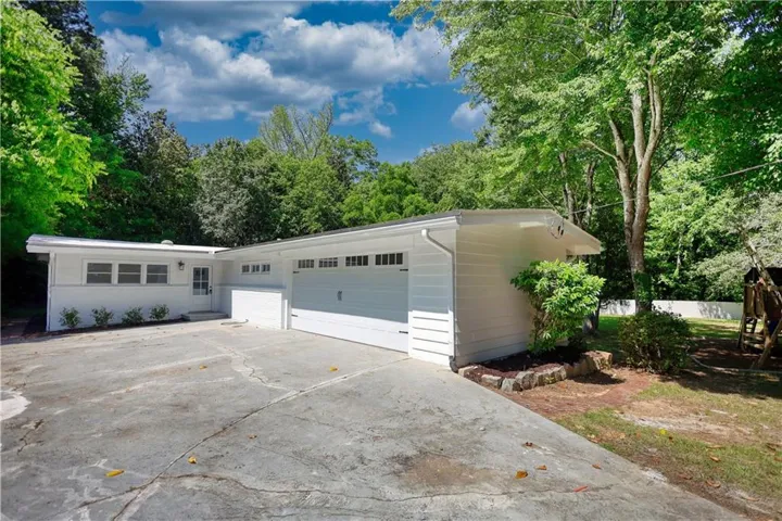 White siding exterior with a two-car garage, multiple windows, and a front entry door