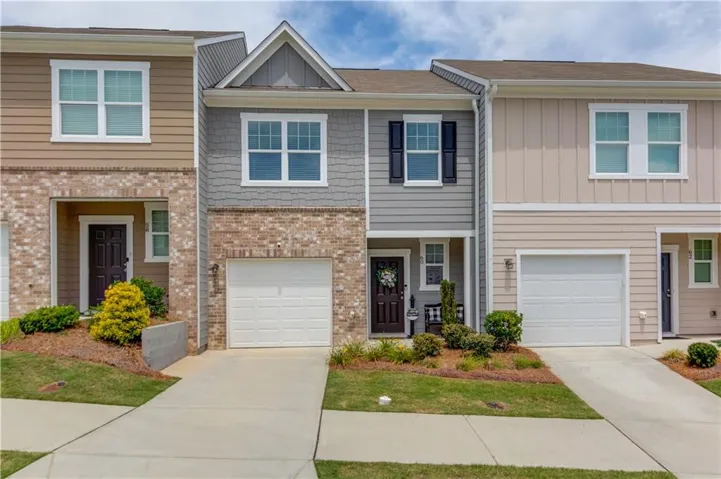 Townhome exterior featuring varied siding materials, brick accents, and individual garage access