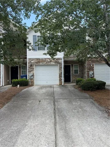 Townhome exterior featuring white horizontal siding and stone veneer accents