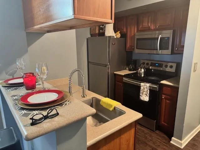 Kitchen with appliances with stainless steel finishes, sink, dark hardwood / wood-style floors, and kitchen peninsula