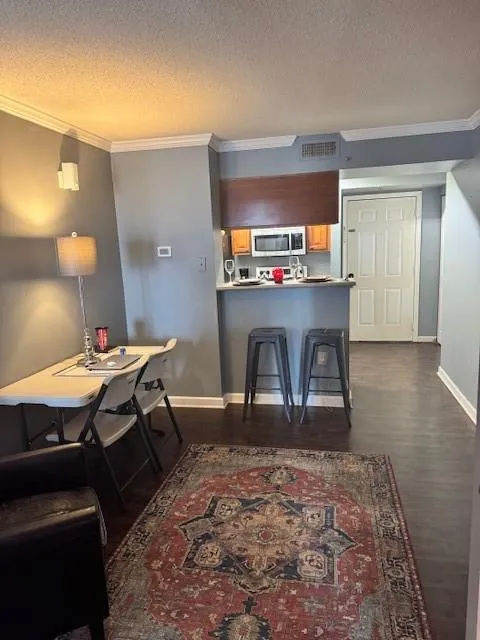 Kitchen with kitchen peninsula, dark hardwood / wood-style floors, a textured ceiling, crown molding, and a kitchen breakfast bar