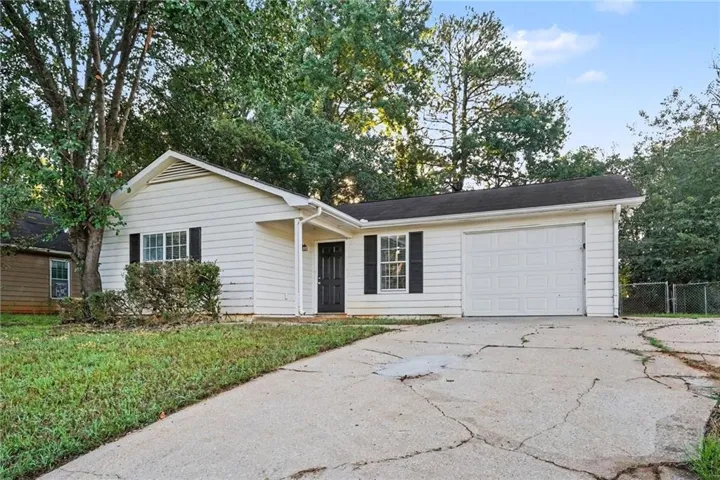 Single-story residence featuring white siding, a dark roof, and an attached single-car garage