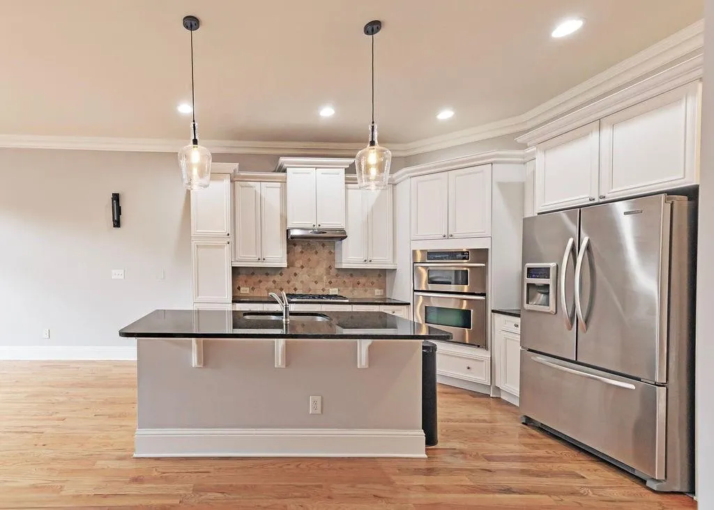 Kitchen Featuring Crown Molding, Light Hardwood Floors, Tiled Backsplash, Huge Kitchen Island. Back Quartz Counter-Tops, And stainless Steel Appliances. Freeze/Fridge Stays!