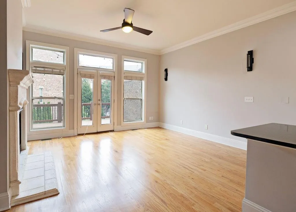 Living/Family Room Featuring Built In Bookcases and  Fireplace With View To Deck, French Doors, Expansive Windows and Light Hardwood Floors.