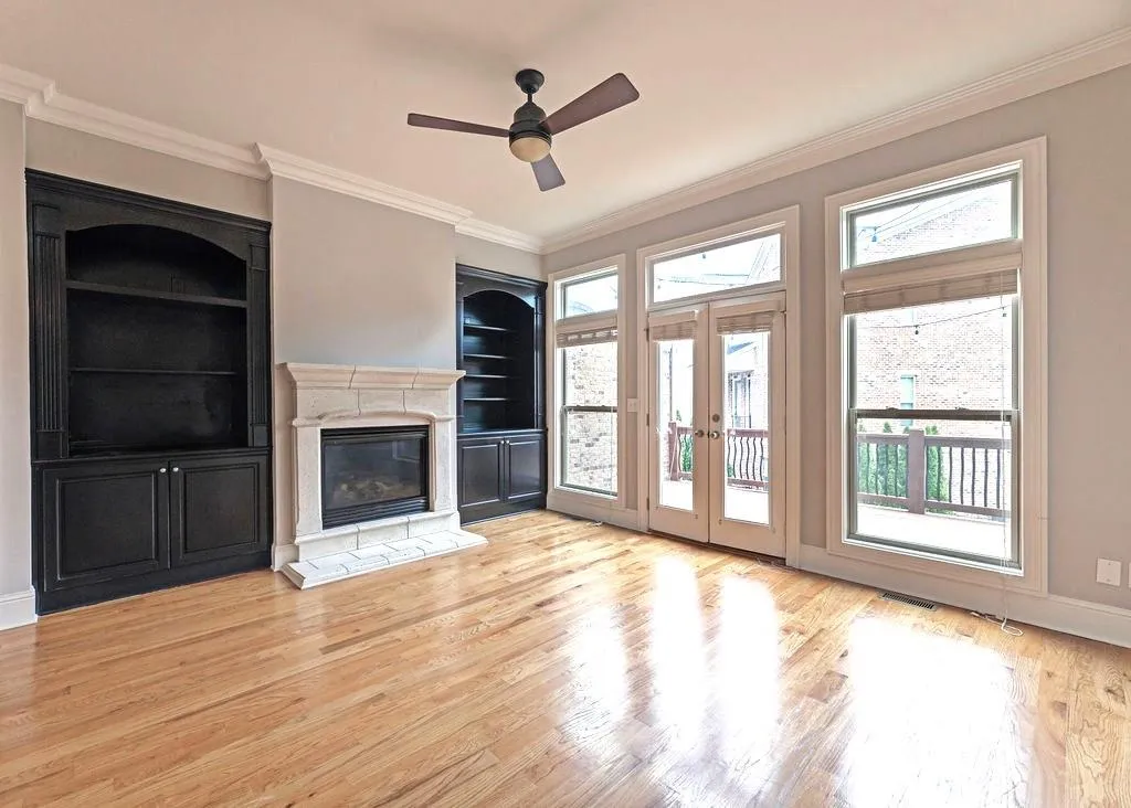 Living/Family Room Featuring Built In Bookcases and  Fireplace With View To Deck, French Doors, Expansive Windows and Light Hardwood Floors.