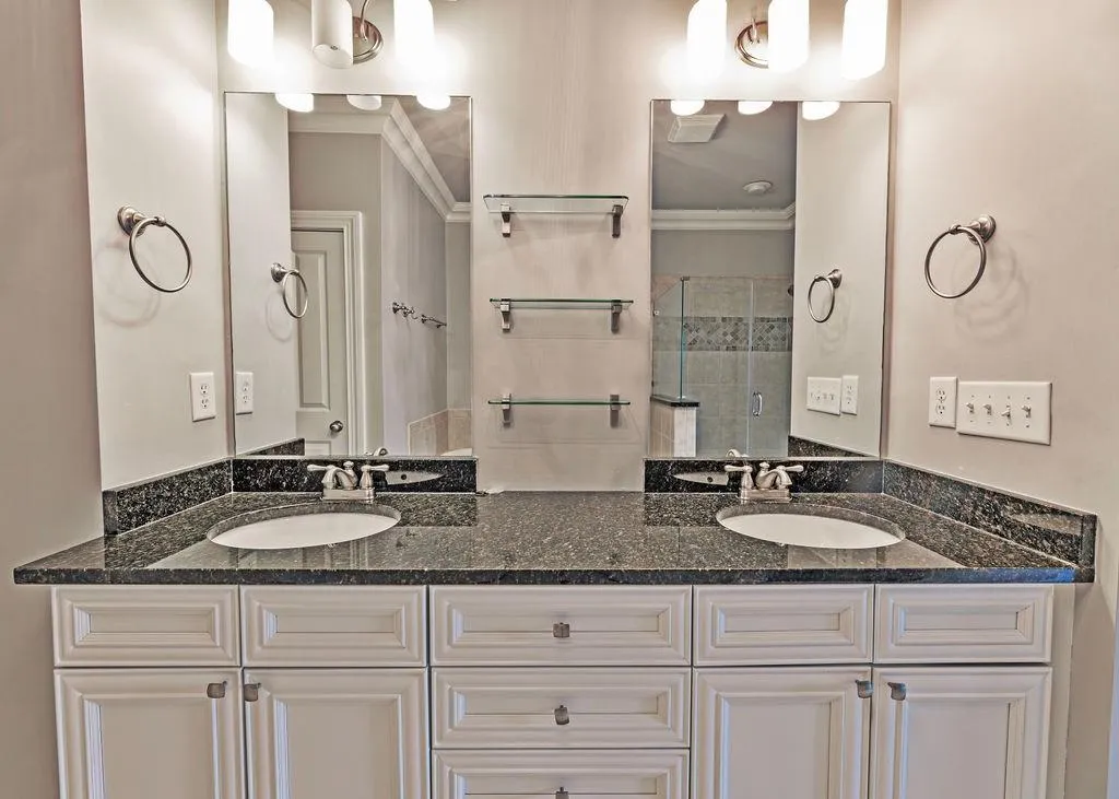 Bathroom Featuring Dual Bowl Vanity and Ornamental Molding.