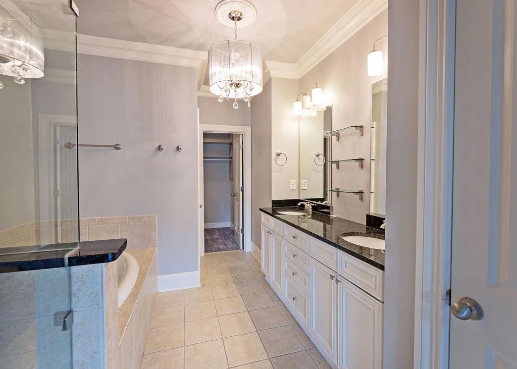 Master Bathroom Featuring Crown Molding, Dual Vanity, Jetted Soaking Tub, Enclosed Separate Shower  and Tiled Floors.