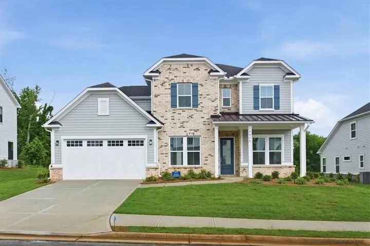Striking two-story Colonial featuring a brick and stone exterior with multi-gable roofline and dark architectural shingles