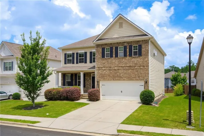 Two-story property featuring brick and siding exterior, an attached garage, covered front porch, and a concrete driveway