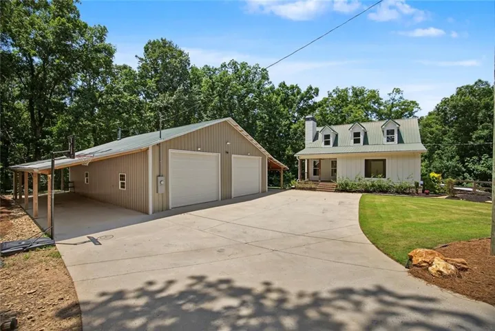 Spacious detached garage with two roll-up doors, an extended covered carport, and a concrete driveway