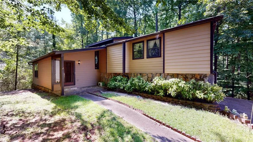 Siding exterior with stone veneer accents, covered entry, and established landscaping