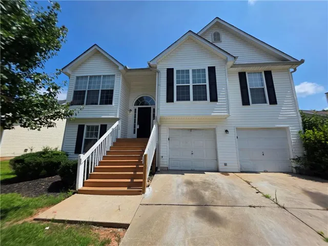 Two-story white siding exterior featuring a prominent front staircase with white railings and wood-finish treads