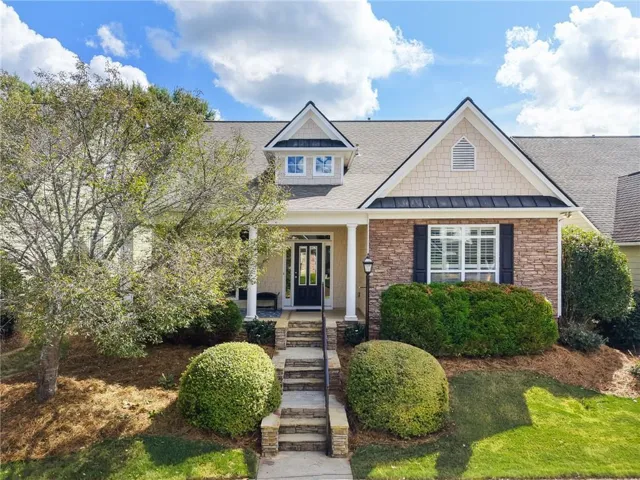 Craftsman-style exterior featuring stone accents, a covered front porch with columns, a stepped stone pathway, and mature landscaping