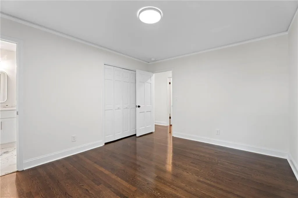Dark wood-finish flooring with white trim, a flush-mount ceiling light, and white bi-fold closet doors