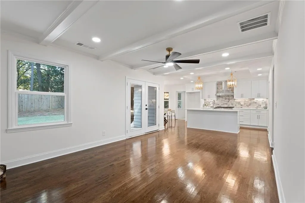 Hardwood flooring, coffered ceiling, recessed lighting, white shaker cabinetry, and a center island with pendant lighting