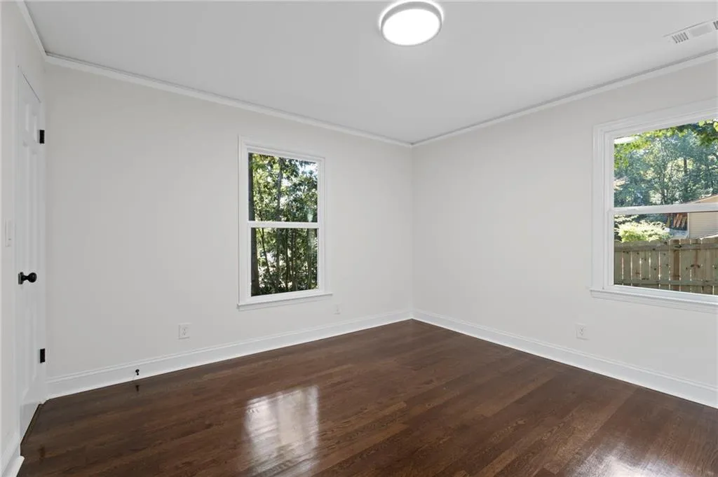 Hardwood flooring, white walls, crown molding, white trim, and a flush mount ceiling light