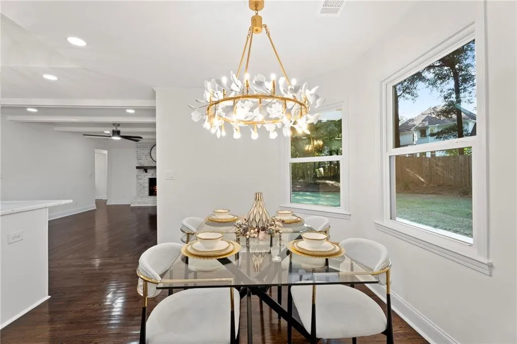Dining area featuring a decorative chandelier, white walls, dark wood-finish flooring, and multiple windows