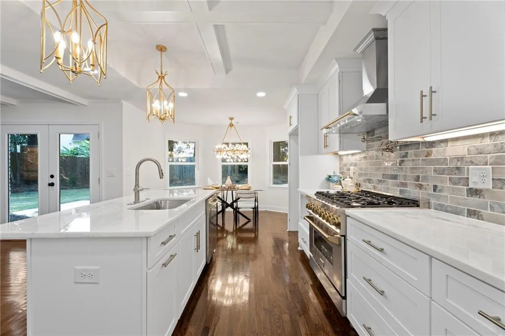 White cabinetry with brushed nickel hardware, stainless steel appliances, white countertops, and a subway tile backsplash