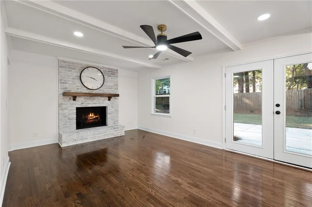 Hardwood flooring and a white brick fireplace with a wood mantel