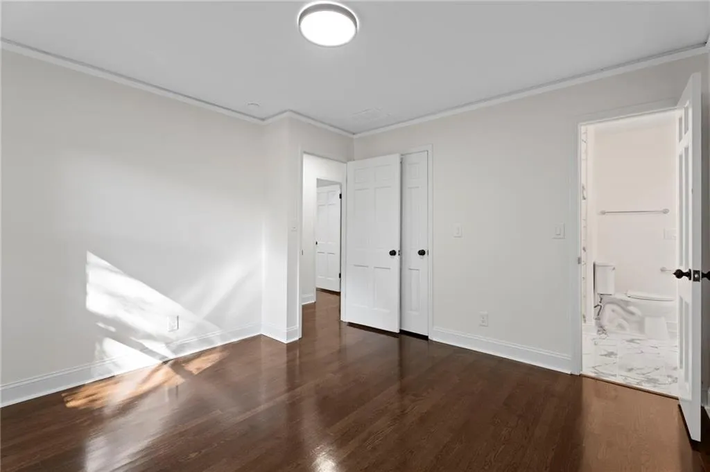 Dark wood-finish flooring with white baseboards, crown molding, and a flush-mount ceiling light fixture