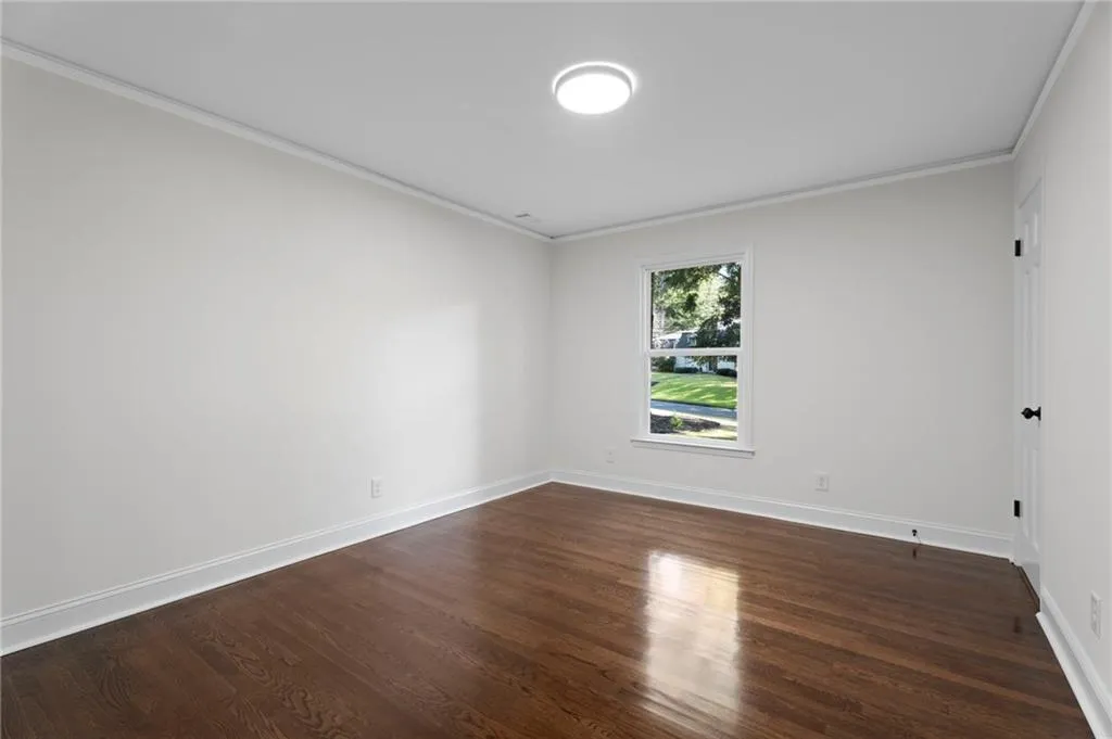Hardwood flooring throughout, crown molding, and a single-pane window with white trim