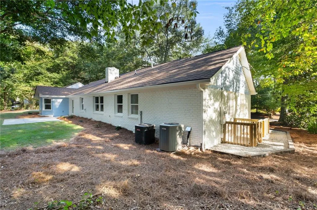 White brick exterior with a pitched roof, multiple windows, and an outdoor patio with wood railing