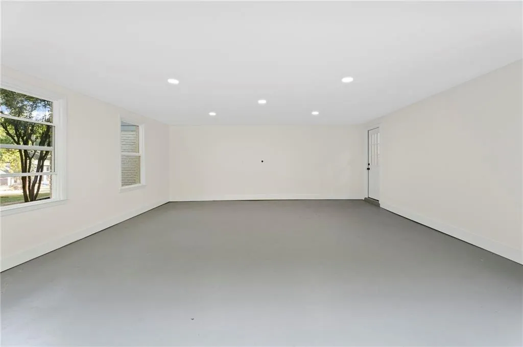 Spacious room featuring two windows, recessed lighting, a smooth ceiling, and painted concrete flooring