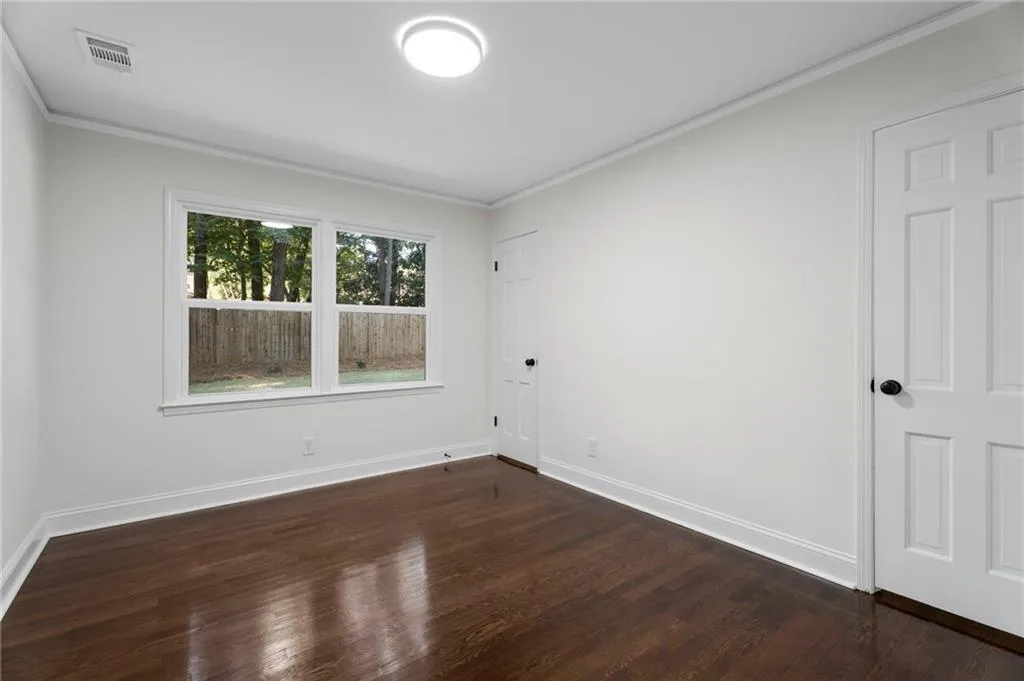 Dark wood-finish flooring, white walls, and a contemporary ceiling light fixture