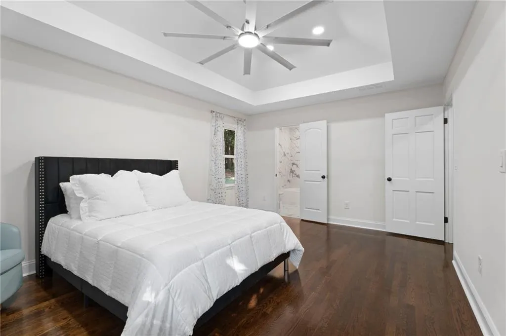 Tray ceiling with recessed lighting and a ceiling fan, wood-finish flooring, and white interior doors