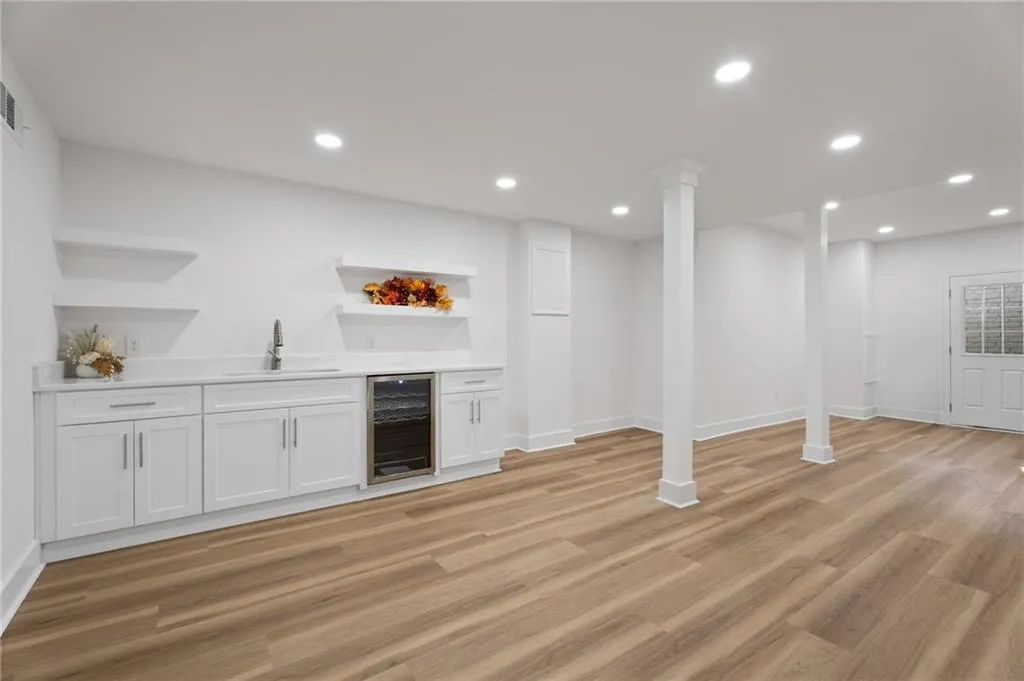 Spacious interior with wood-finish flooring, recessed lighting, and white support columns