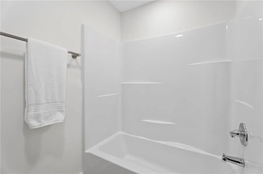 White fiberglass tub and shower combination with chrome fixtures