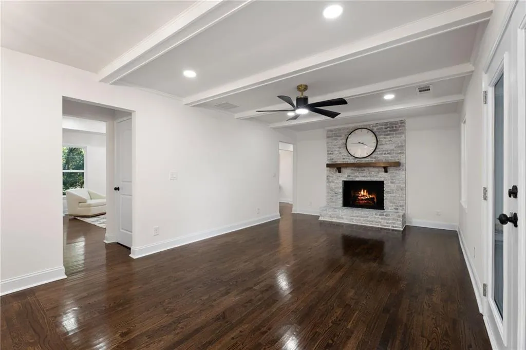 Hardwood flooring, coffered ceiling, recessed lighting, brick fireplace with wood mantle, and a ceiling fan
