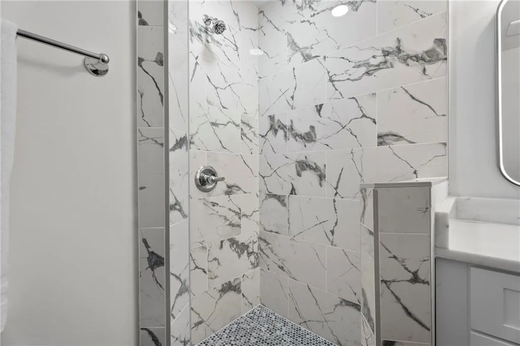 Walk-in shower with large-format stone-look tiles, chrome shower fixtures, and a tiled shower floor