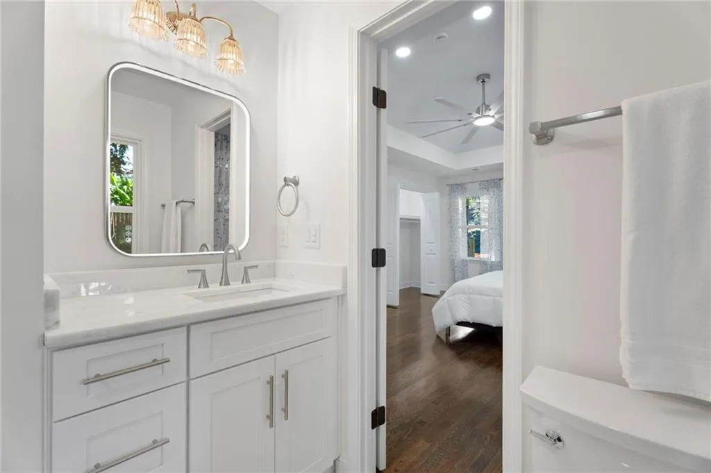 Spa-inspired primary bathroom featuring a white shaker-style vanity with dual sinks, quartz countertop, and polished chrome fixtures