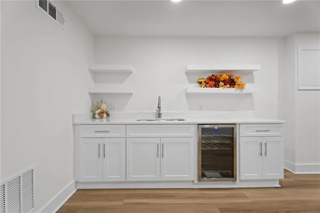 White cabinetry with stainless steel hardware, a built-in beverage cooler, and a stainless steel sink with a gooseneck faucet