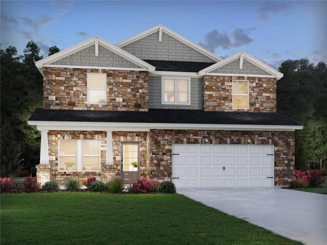 Two-story exterior with stone and shingle siding, a front entry with sidelights, a two-car garage, and established foundation plantings