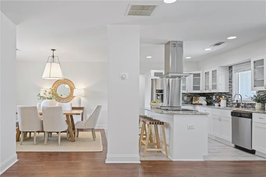Kitchen with light stone countertops, glass insert cabinets, light wood-style floors, backsplash, and a kitchen bar Kitchen with light stone countertops, glass insert cabinets, light wood-style floors, backsplash, and a kitchen bar