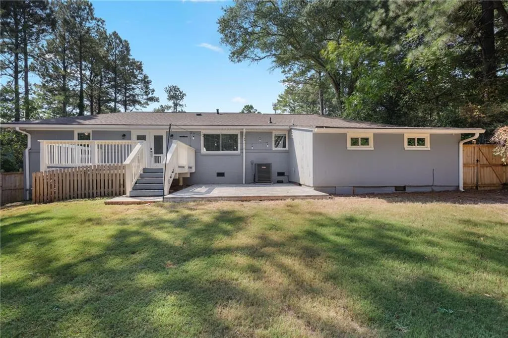 Back of property with a patio area, crawl space, a wooden deck, and a shingled roof Back of property with a patio area, crawl space, a wooden deck, and a shingled roof