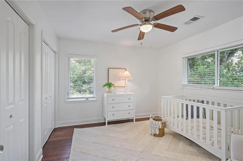 Bedroom with two closets, dark wood-style flooring, a nursery area, and a ceiling fan Bedroom with two closets, dark wood-style flooring, a nursery area, and a ceiling fan