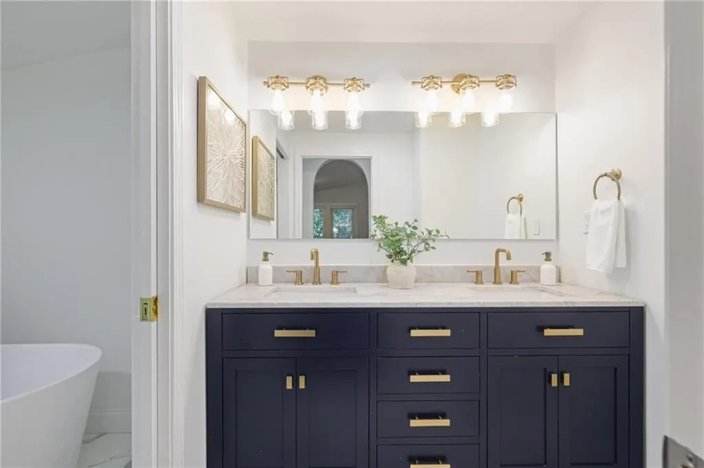Bathroom featuring a soaking tub, double vanity, and marble finish floors Bathroom featuring a soaking tub, double vanity, and marble finish floors