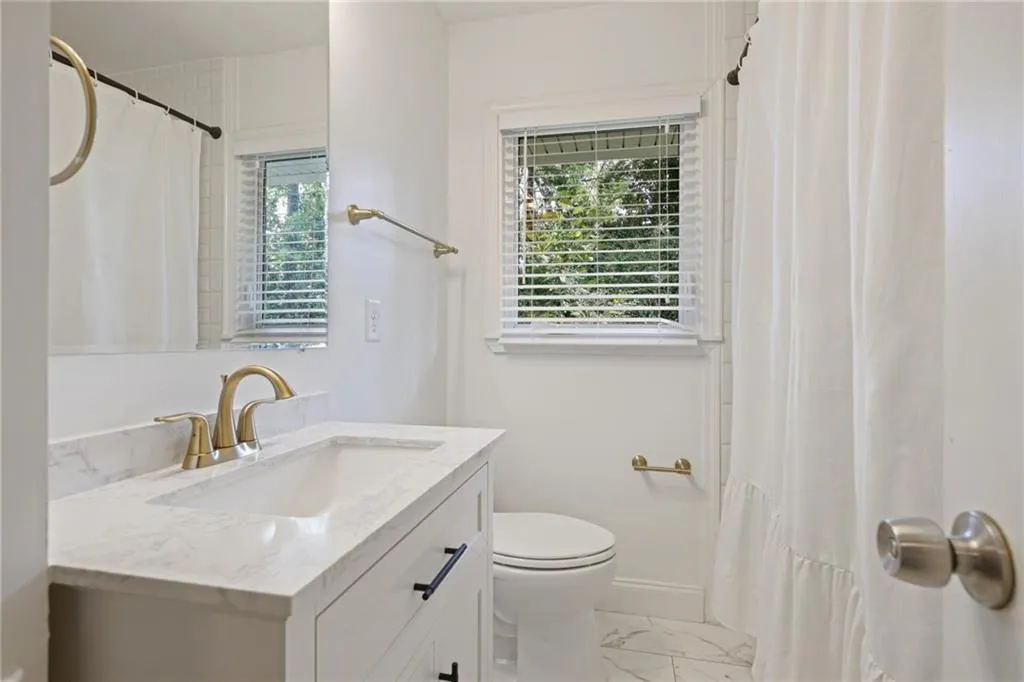 Bathroom with vanity, light marble finish flooring, and a shower with shower curtain Bathroom with vanity, light marble finish flooring, and a shower with shower curtain