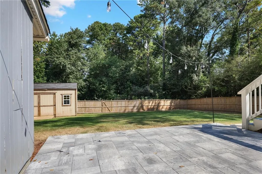 Fenced backyard with a shed, a patio, and view of scattered trees Fenced backyard with a shed, a patio, and view of scattered trees
