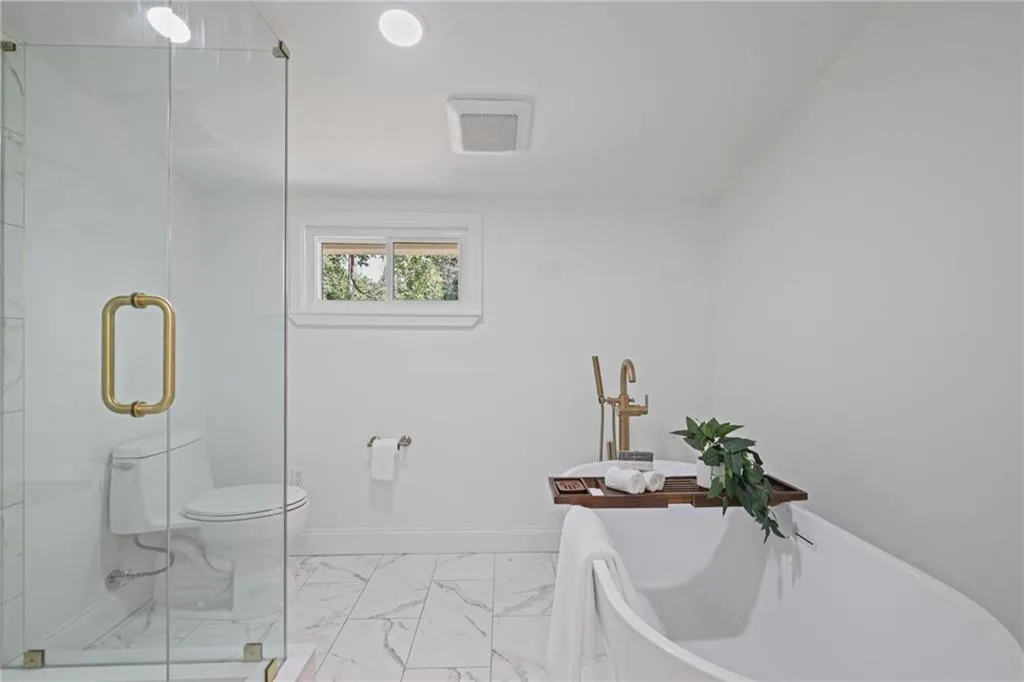 Bathroom with light marble finish flooring, a freestanding bath, and a marble finish shower Bathroom with light marble finish flooring, a freestanding bath, and a marble finish shower