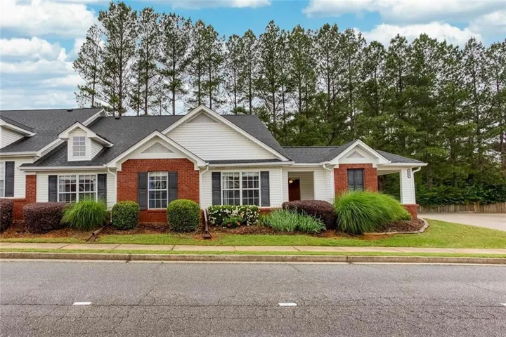 Brick and siding exterior with dark shutters, gabled roofline, and landscaped shrubbery