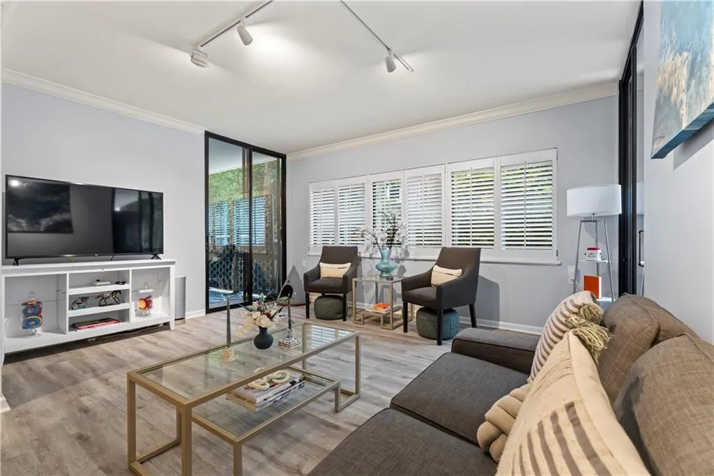 Living area with ornamental molding, plenty of natural light, wood finished floors, and rail lighting