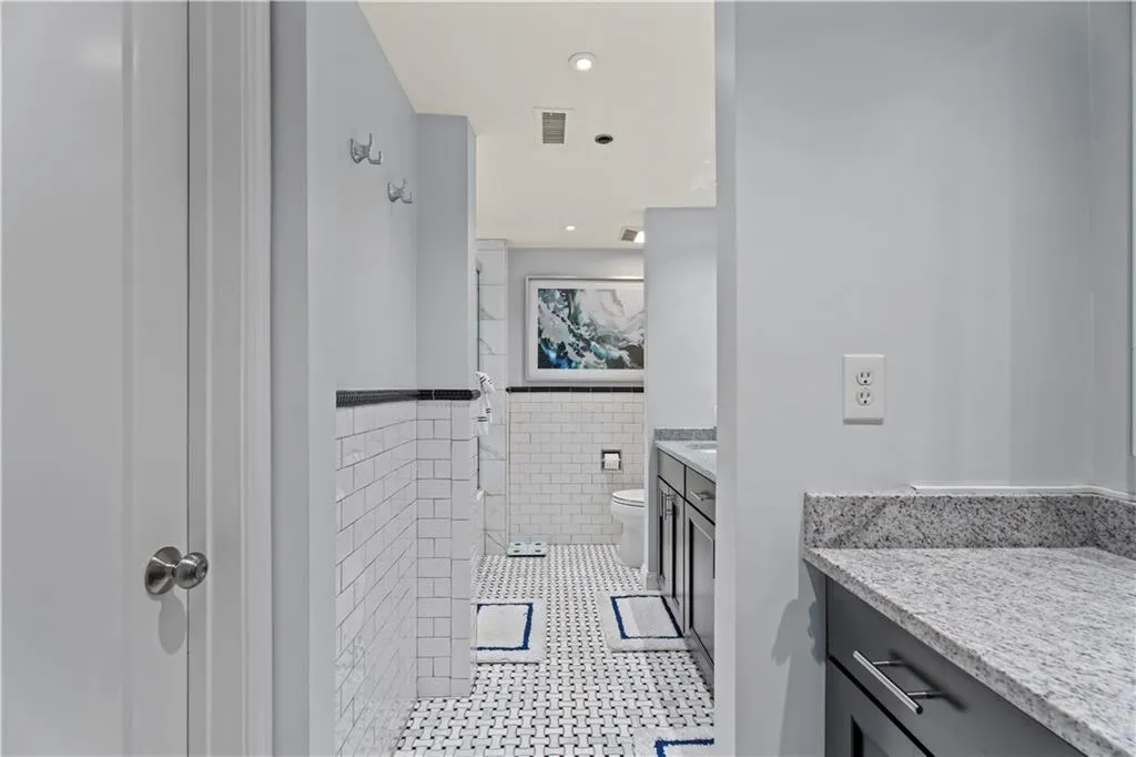 Bathroom featuring tile walls, vanity, wainscoting, recessed lighting, and a shower